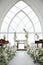 Wedding ceremony in the chapel for intimacy family and friends. Sunny outdoors afternoon natural light. Flowers arrangement for de