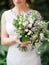 Wedding ceremony. Young bride holds oversized wedding bouquet with blue thistle flowers, jana roses, eucalyptus leaves