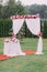 The wedding composition of the wedding arch and table decorated with colourful flowers and hanging beads.