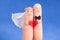Wedding concept - newlyweds painted at fingers against blue sky