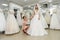 Wedding consultant helps bride fit wedding dress in salon