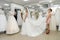Wedding consultant helps bride fit wedding dress in salon