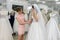 Wedding consultant helps bride fit wedding dress in salon