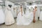 Wedding consultant helps bride fit wedding dress in salon