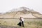 Wedding couple on a background of snowy mountains. The bride in a black dress and groom are hugging in a field of moss