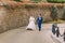 Wedding couple, cheerful bride and loving groom strolling in park near sandstone wall