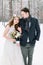 Wedding couple close-up. Bride holding the bouquet, with cotton wreath, and groom on the background of a winter