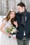 Wedding couple close-up. Bride holding the bouquet, with cotton wreath, and groom on the background of a winter