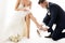 Wedding Couple, Elegant Groom in Suit wearing shoe to Bride Leg in White Dress