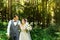 A wedding couple enjoys walking in the woods. Newlyweds hug and hold hands