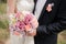 Wedding couple hugging, the bride holding a bouquet of flowers in her hand, the groom embracing