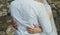 Wedding couple is hugging near the stone wall. Bride in puffy tulle dress and groom in white shirt. Golden rings on hands.