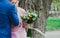 Wedding couple kisses near the tree in the green forest or park. Plus size bride in pink lace dress holds bouquet from beige and