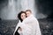 Wedding couple near Skogafoss waterfall. The bride and groom covered with a woolen blanket, where hugging. Snow is