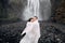 Wedding couple near Skogafoss waterfall. The bride and groom covered with a woolen blanket, where hugging. Snow is