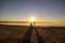 Wedding couple on the sea beach watching sunset. Sunny summer photo. Bride with hair down in off shoulder dress with train. Ocean