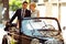 A wedding couple sits on a black retro cabriolet