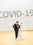 wedding couple standing in front of a large lettering with covid 19 and celebrating alone without party guests