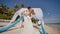 A wedding couple on a tropical beach next to the ocean. Kiss under the arch with white and blue air wings flying in the