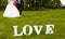 Wedding couple unfocused and love word on the grass