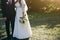 Wedding couple walking in the green park. Curvy bride in white lace dress and groom are holding hands. Overweight happy people.