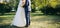Wedding couple walking in the green park. Curvy bride in white lace dress and groom are holding hands. Overweight happy people.