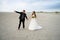 Wedding couple walking on sandy beach. Barefoot bride and groom. Husband pointing at something interesting by hand