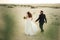 Wedding couple walking on sandy beach. Bride and groom rear view. Barefoot husband. Wedding day concept.