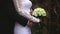 On a wedding day the groom strokes the bride`s hand, the wedding bouquet