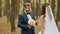 Wedding day. Happy couple and touching. The groom embraces the bride in a pine forest and gives a bouquet. The bride was