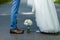 Wedding details: classic brown and blue shoes of bride and groom. Bouquet of roses standing on the ground between them. Newlyweds