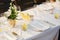 Wedding dinner table reception. Glass transparent bath with sliced lemons and a bouquet of white Alstromeri, on the