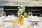 Wedding dinner table reception. Glass transparent bath with sliced lemons and a bouquet of white Alstromeri, on the