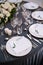 Wedding dinner table reception. White round plates on a round table with gray tablecloth, white Chiavari chairs with