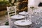 Wedding dinner table reception. White round plates on a round table with gray tablecloth, white Chiavari chairs with