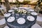 Wedding dinner table reception. White round plates on a round table with gray tablecloth, white Chiavari chairs with