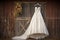 wedding dress on hanger against a rustic barn wall