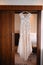 a wedding dress on hanger hangs in the doorway, the morning of a sissy, the bride`s outfit before the wedding, the dress is