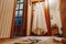 A wedding dress hanging in a doorway in a room on a brown background. Family, marriage, holiday, celebration, wedding