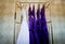 Wedding dress and purple bridesmaid dresses hanging on a bell cart