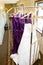 Wedding dress and purple bridrsmaid dresses hanging on a bell cart