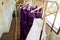 Wedding dress and purple bridrsmaid dresses hanging on a bell cart