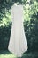 Wedding elegant lace wedding white dress hanging on a hanger under tree