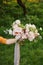 wedding fine-art bouquet in the hands of the bride, David Austin Rose, green background one hand holds only a bouquet
