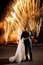 Wedding fireworks. Back view of bride and groom hugging in the night on firework and salute background on night sky