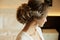 Wedding hairstyle of beautiful and fashionable brown-haired model girl in a lace dress, with earrings and jewelry in her