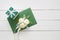 Wedding invitation card or Valentines Day letter in green envelope decorated with white rose flowers and gift box.