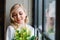 Wedding morning of the bride. Exquisite blonde in a delicate peignoir standing near the window with a bouquet of flowers in her