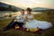 Wedding outdoor shot. Attractive happy young newlyweds are clinking glasses with champagne during their picnic on the