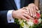 Wedding pastel bouquet closeup in front of couple - groom and bride`s hands with elegant manicure. Flowers lay on the dress with